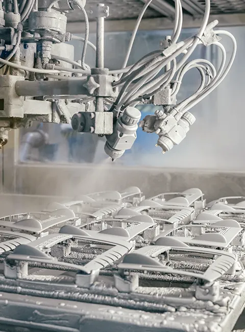 Robot przemysłowy automatycznie maluje kilka części plastikowych w zakładzie produkcyjnym za pomocą techniki natryskowej.