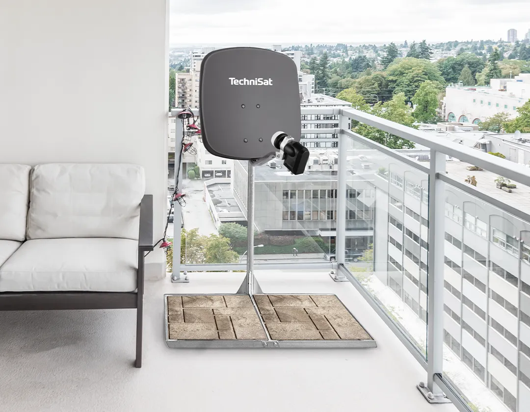 Sat-Schüssel auf standfester Balkonhalterung mit Pflastersteinen beschwert – ideale Lösung für Mietwohnungen mit Balkon.