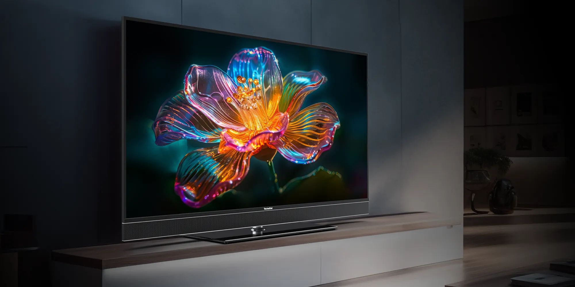 Ein UHD-Smart-TV von TechniSat auf einem Regal im Wohnzimmer mit detaillierter, farbenfroher Blume im Bildschirm.